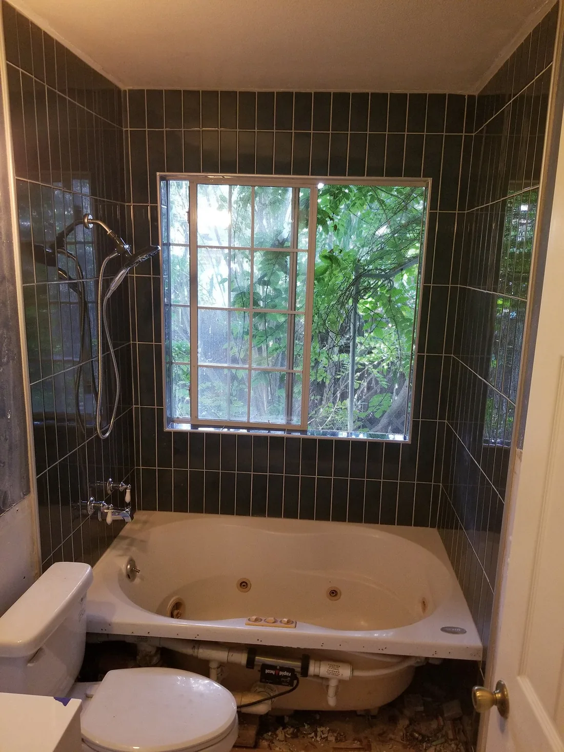 Dark tiled shower with window and wall-mounted fixtures