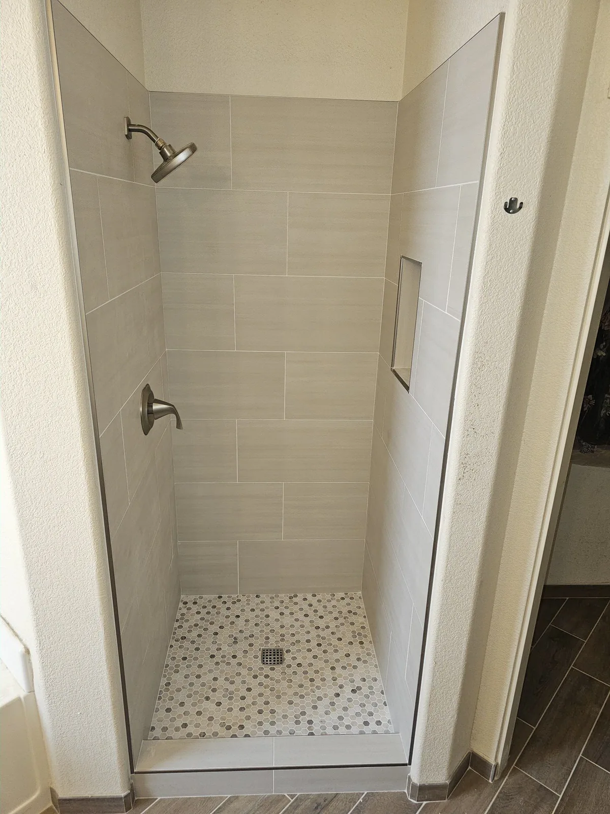 Finished walk-in shower with large-format neutral tile installed by Valley Tile Pros Inc.